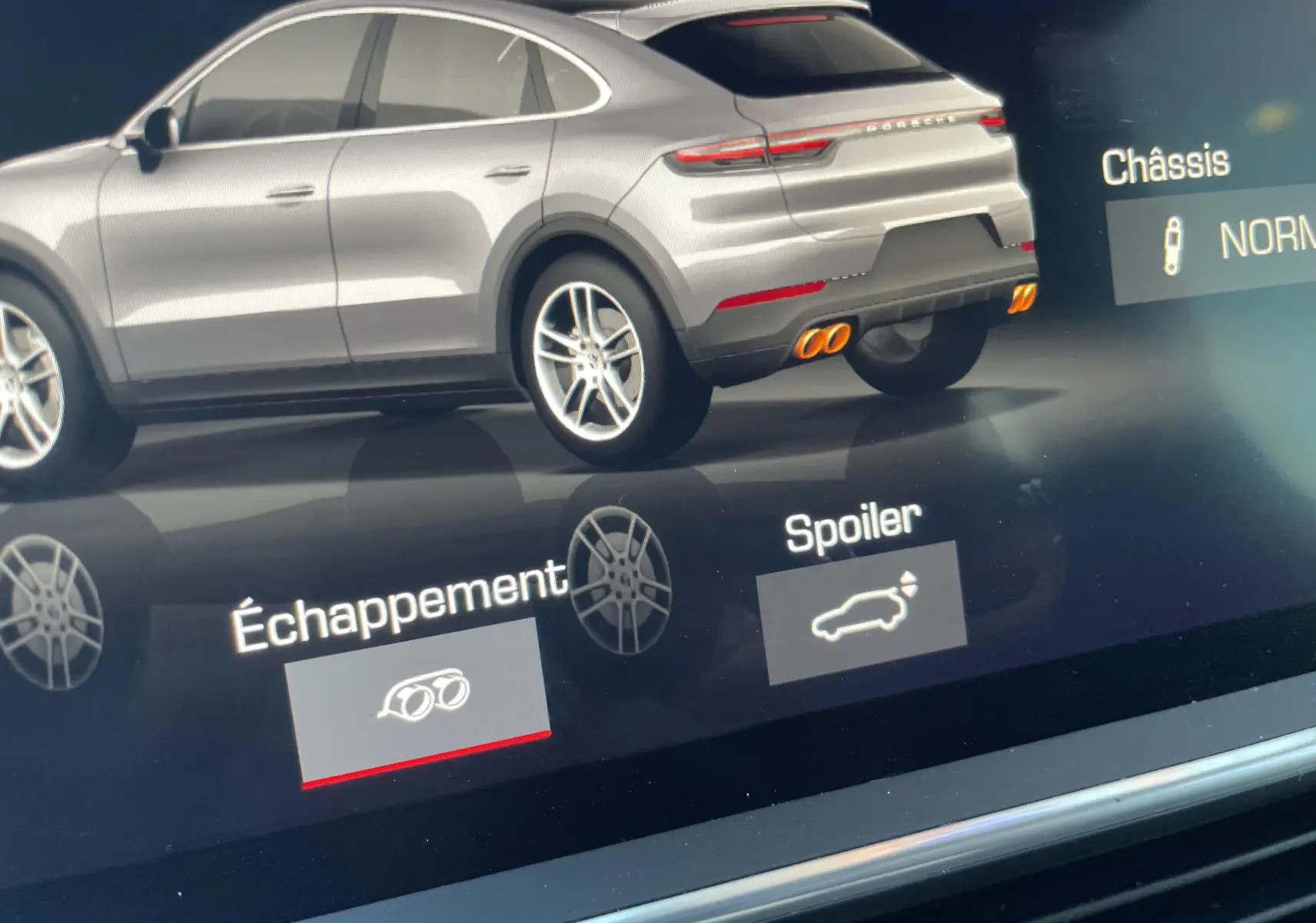 Vue arrière droite du Porsche Cayenne Coupé hybride noir, mettant en valeur les doubles sorties d’échappement sport oranges.