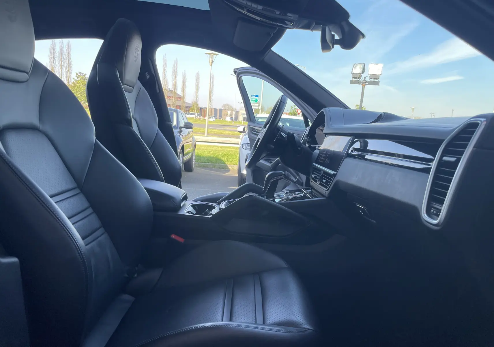 Vue intérieure côté conducteur du Porsche Cayenne Coupé E-Hybrid 2021 avec sièges cuir noirs et tableau de bord moderne.