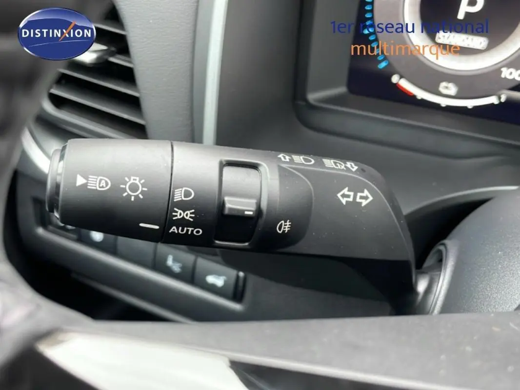 Gros plan sur la commande des feux et clignotants du Nissan Qashqai blanc 2025, intérieur noir.