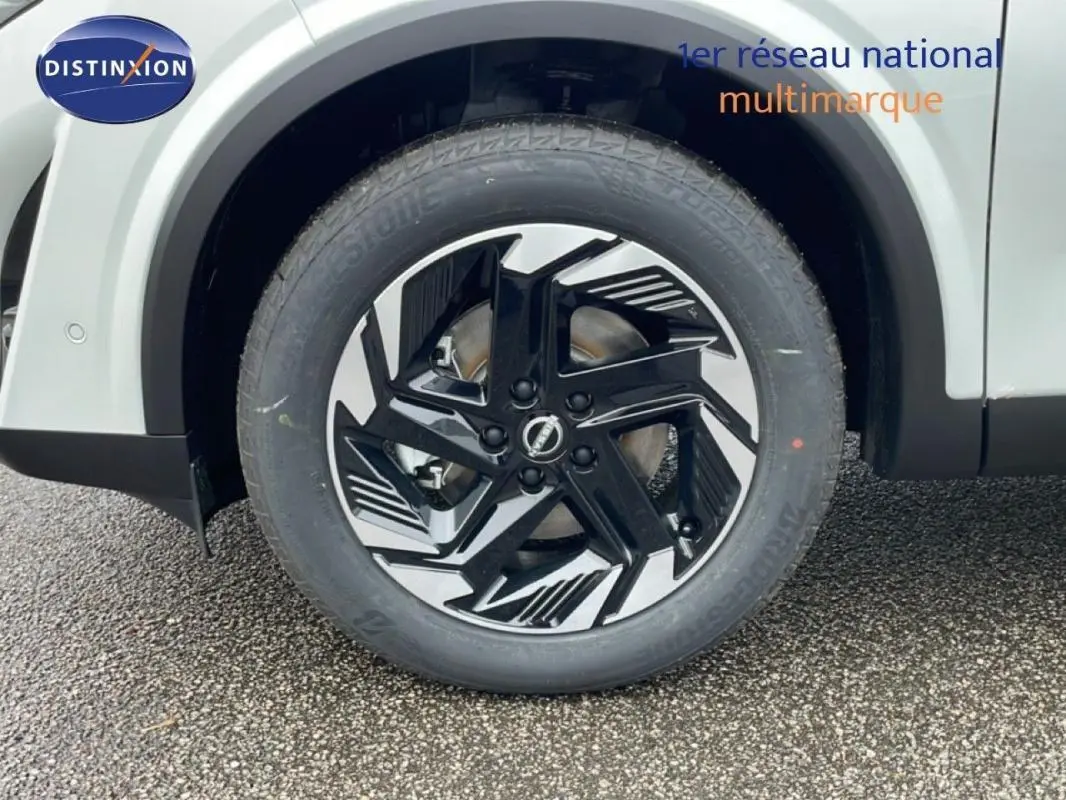 Gros plan sur la jante aluminium noire et argentée du côté gauche du Nissan Qashqai blanc 2025.