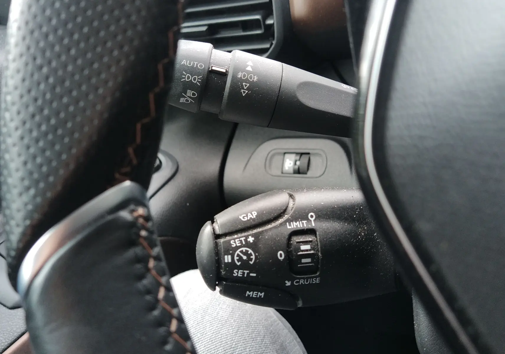 Gros plan sur les commandes au volant du Peugeot Rifter 1.5 BlueHDI 130ch GT, avec boutons de régulateur de vitesse et éclairage.