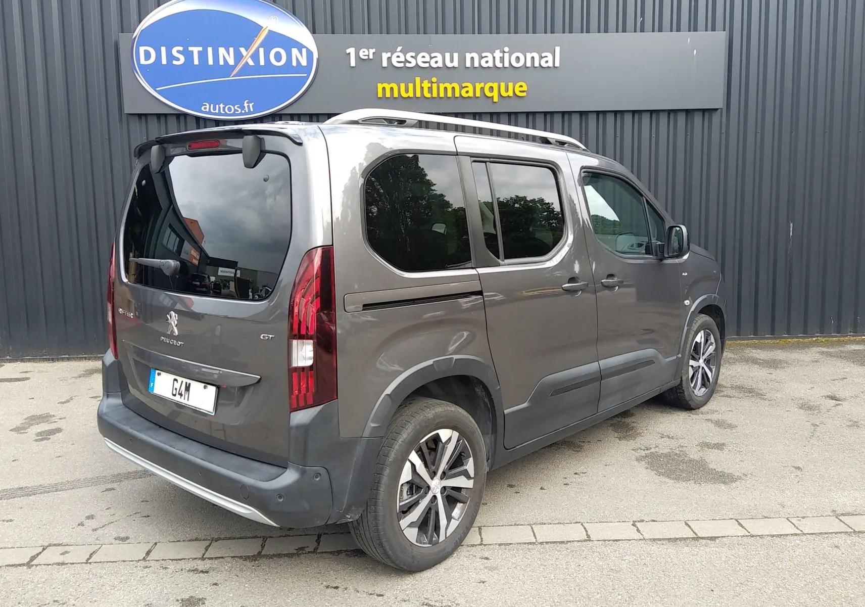 Vue 3/4 arrière droite d’un Peugeot Rifter GT 1.5 BlueHDI gris platinium avec vitres teintées et jantes alliage.