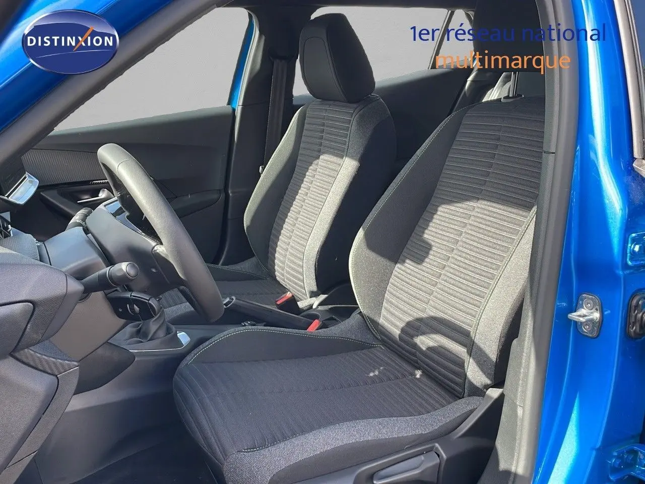Intérieur avant du Peugeot 2008 bleu Vertigo, montrant les sièges tissu gris et la boîte manuelle côté gauche.