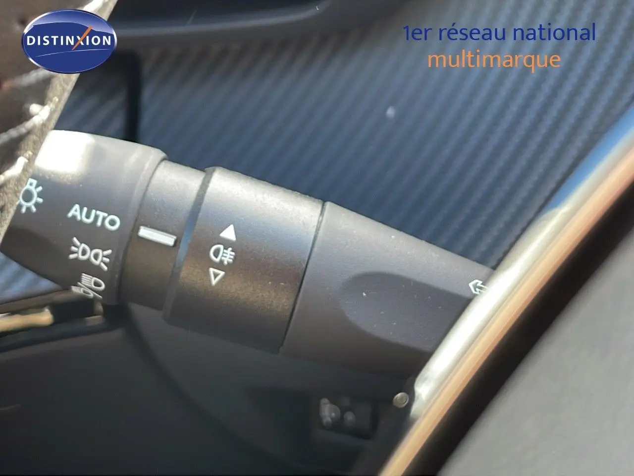 Gros plan sur la commande des phares et clignotants dans l'habitacle d'un Peugeot 2008 bleu Vertigo Metal 2024.