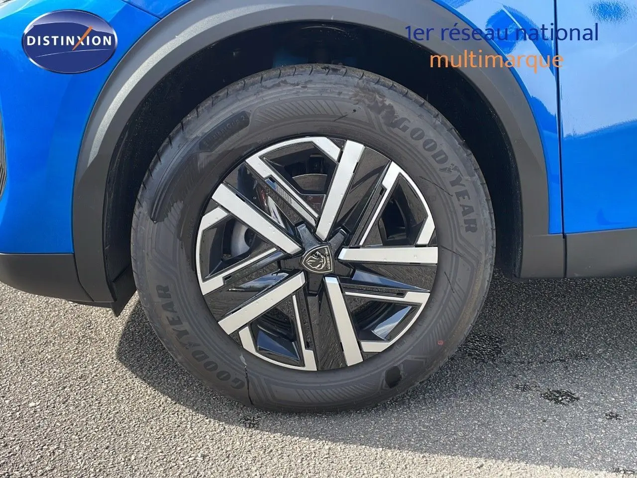 Gros plan sur la roue avant gauche d'un Peugeot 2008 bleu Vertigo Metal avec jante alliage noire et argent.