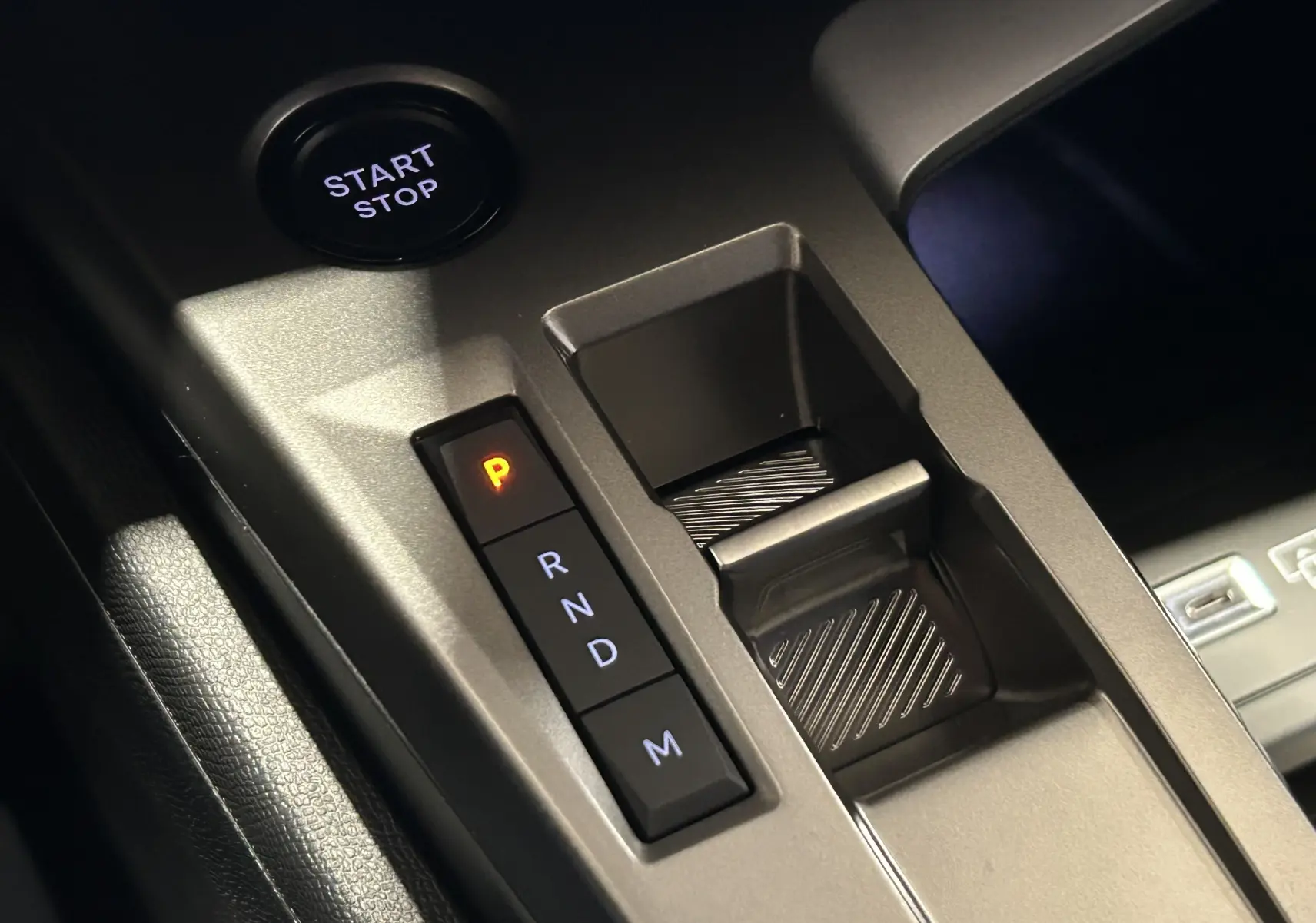 Gros plan sur la console centrale de la Peugeot 308 HYBRID 145 GT avec bouton start/stop et sélection de boîte auto en mode parking.