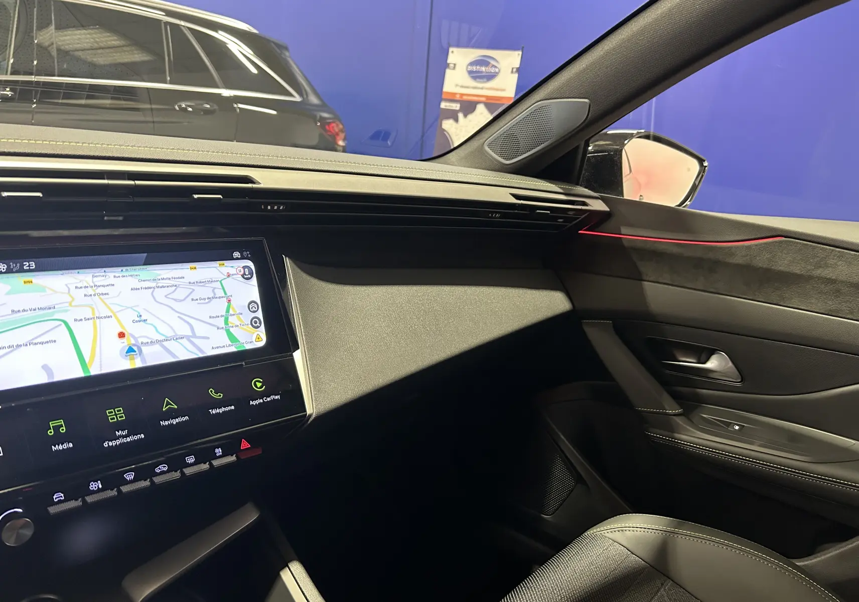 Vue intérieure côté passager du Peugeot 308 gris Selenium, avec écran tactile GPS et éclairage d'ambiance rouge.