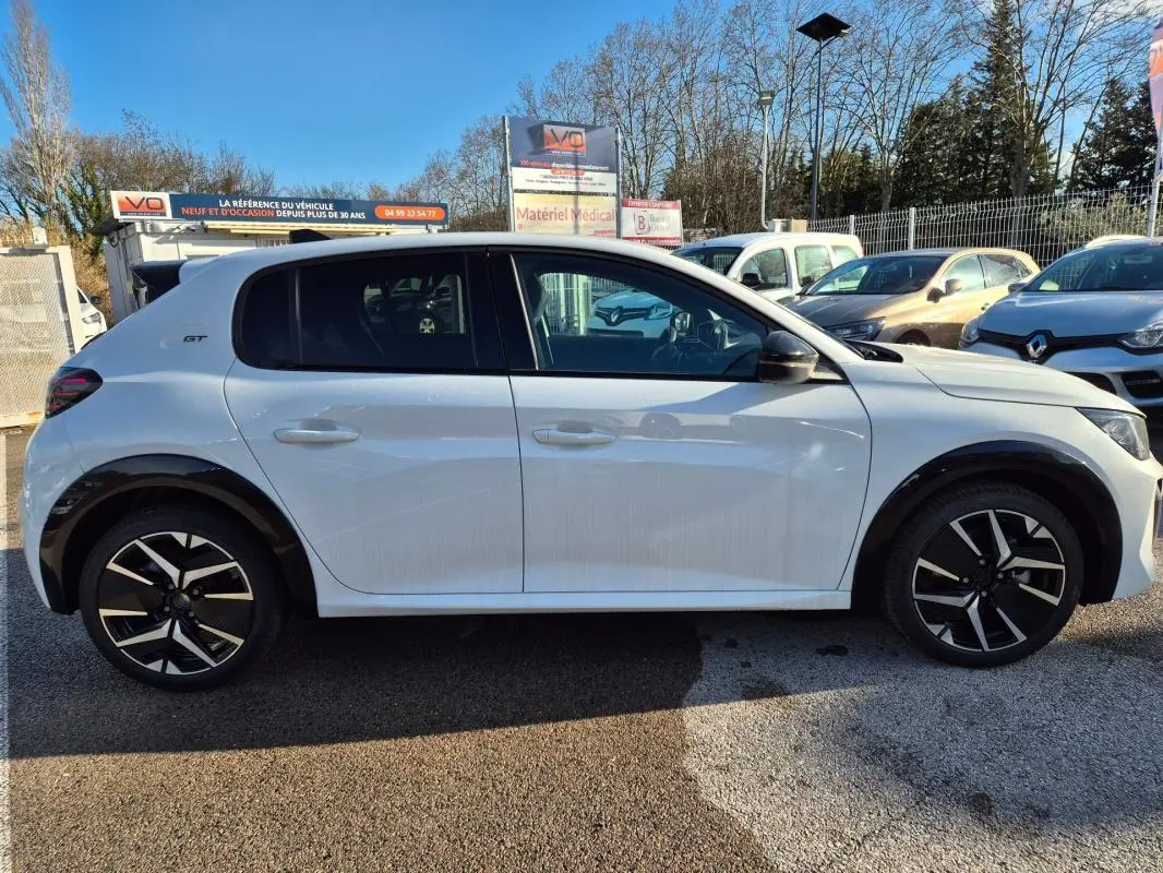Profil droit de la Peugeot 208 Hybrid 136 GT blanche avec jantes alliage 17 pouces et logo GT sur aile arrière.