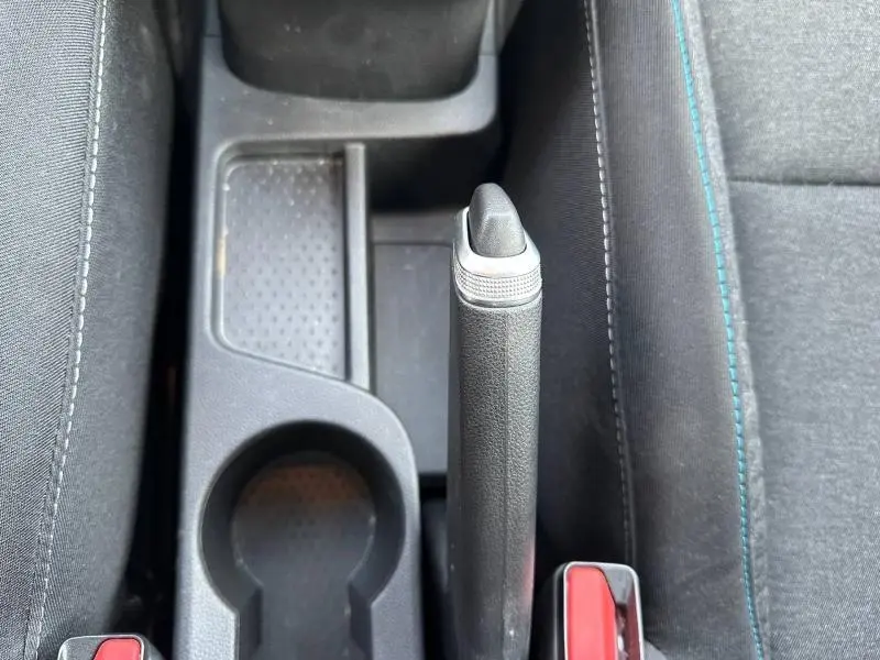 Vue plongeante sur le frein à main manuel et porte-gobelets noirs de l'intérieur tissu du Renault Captur blanc nacré/noir.