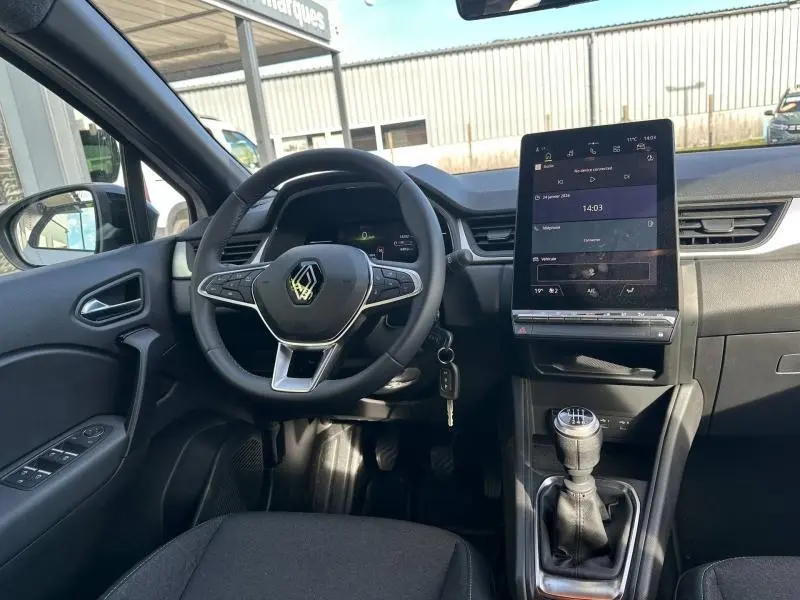 Vue intérieure côté conducteur du Renault Captur 2025, volant multifonction noir et écran tactile vertical central.