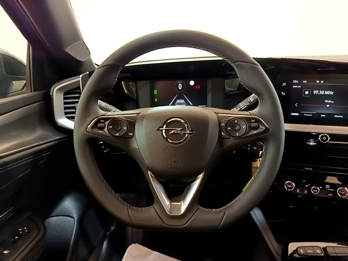 Vue intérieure centrée sur le volant cuir noir de l'Opel Mokka 2024 avec tableau de bord digital et écran tactile.