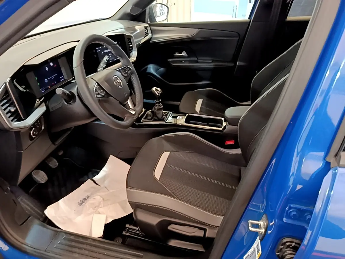 Vue intérieure côté conducteur de l’Opel Mokka bleu 2024, volant cuir, tableau de bord digital et boîte manuelle.