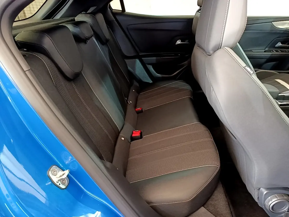 Vue intérieure côté arrière gauche de l’Opel Mokka bleu 2024, montrant la banquette arrière noire avec surpiqûres contrastées.