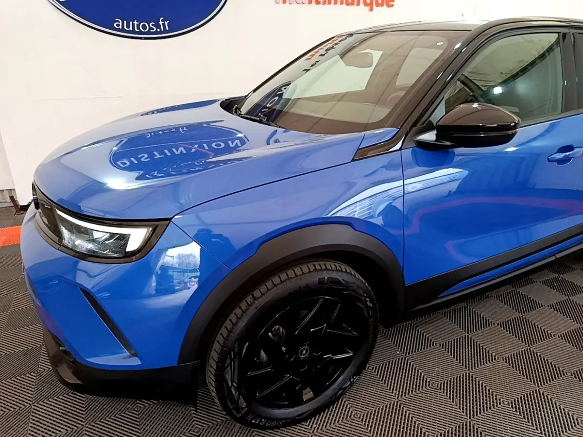 Vue 3/4 avant gauche d’un Opel Mokka bleu 2024 avec jantes noires et rétroviseurs noirs brillants.
