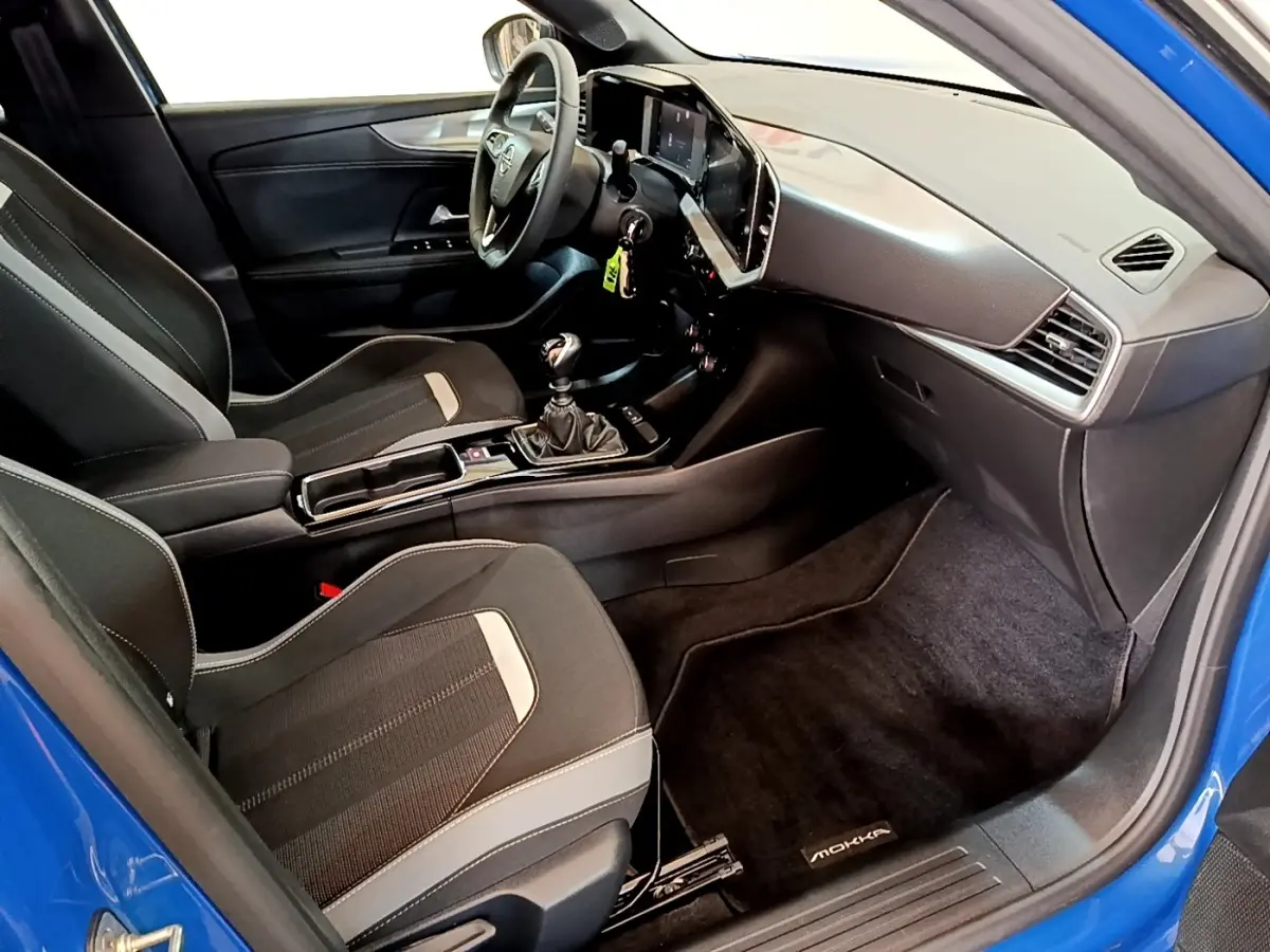 Intérieur avant droit de l’Opel Mokka bleu 2024, avec tableau de bord moderne et boîte manuelle visible.