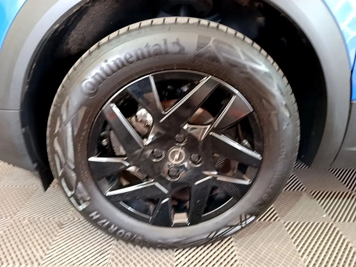 Gros plan sur la roue avant droite noire avec jante en alliage du SUV Opel Mokka bleu 2024.