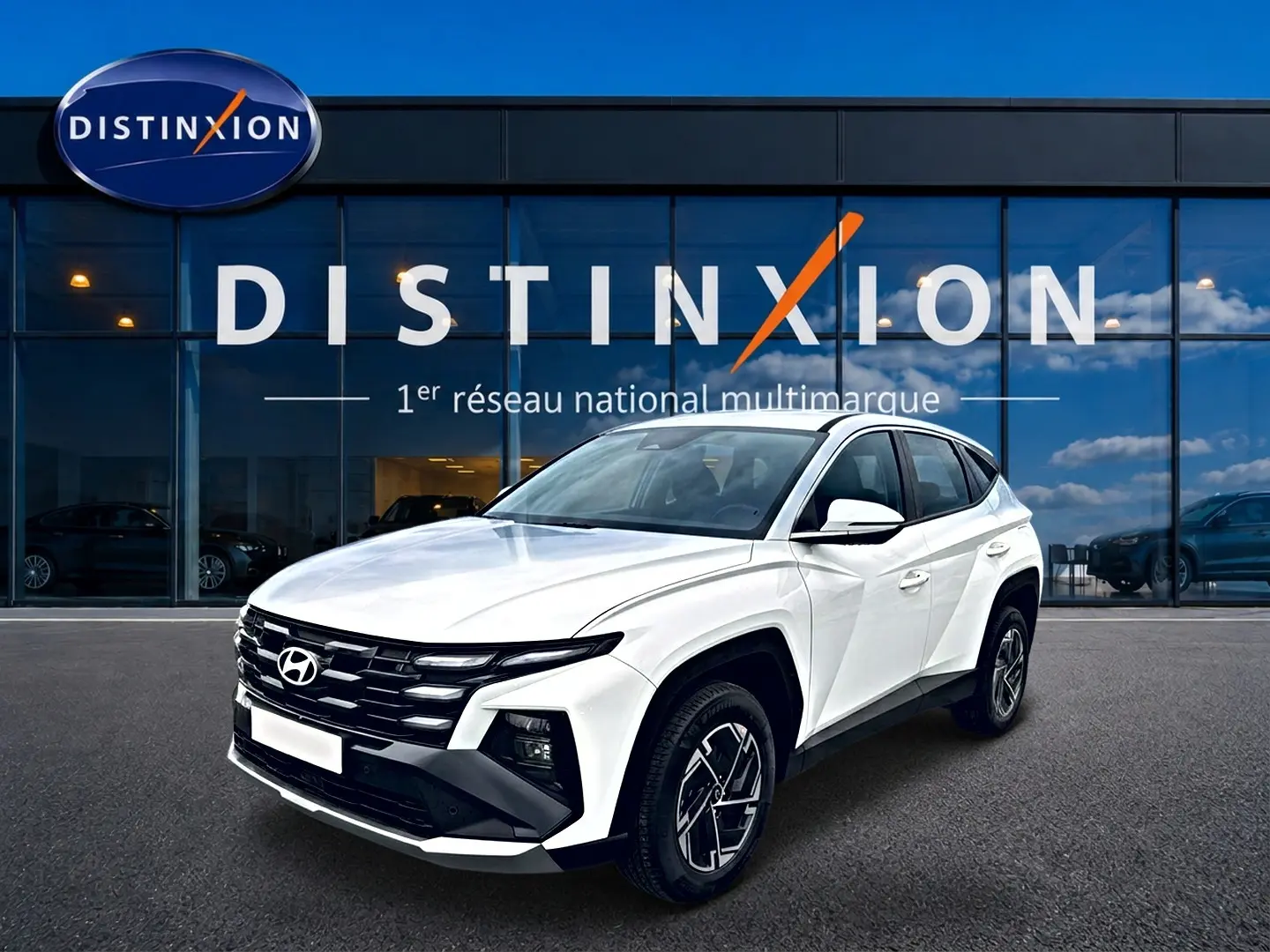Vue 3/4 avant d'un Hyundai Tucson blanc 2026 devant une vitrine avec logo Distinxion.