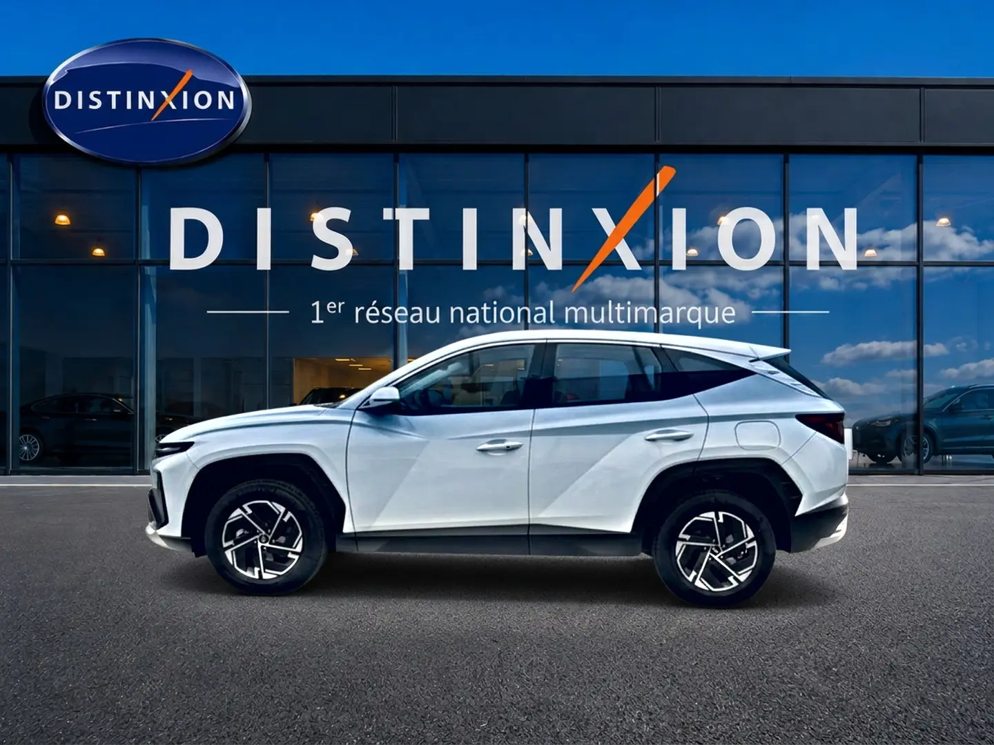 Hyundai Tucson 2026 blanc en profil droit devant une vitrine avec logo Distinxion visible.
