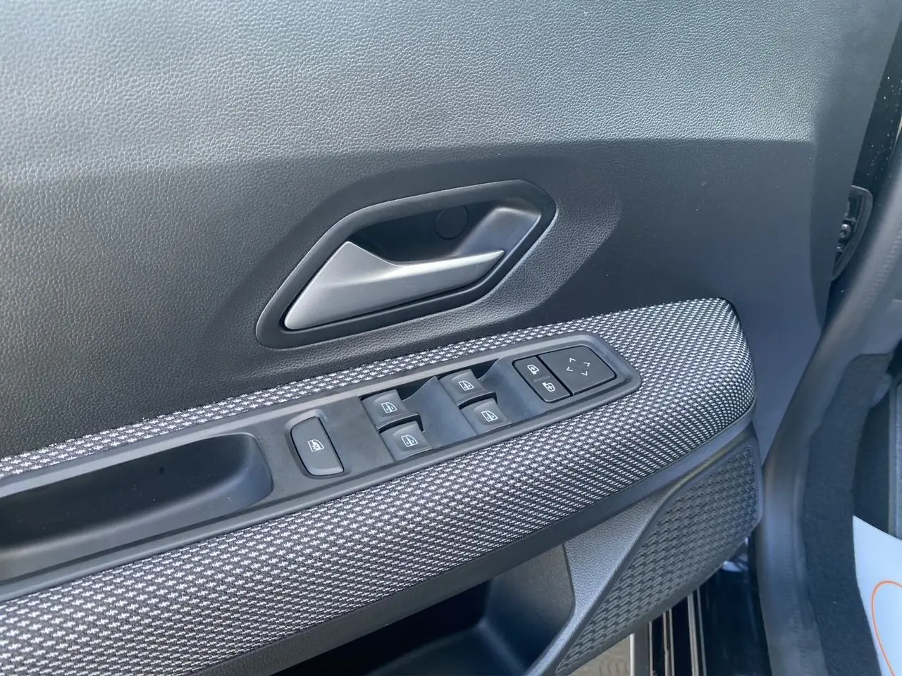 Détail de la porte côté conducteur de la Dacia Sandero Stepway noire avec commandes électriques et habillage tissu noir.