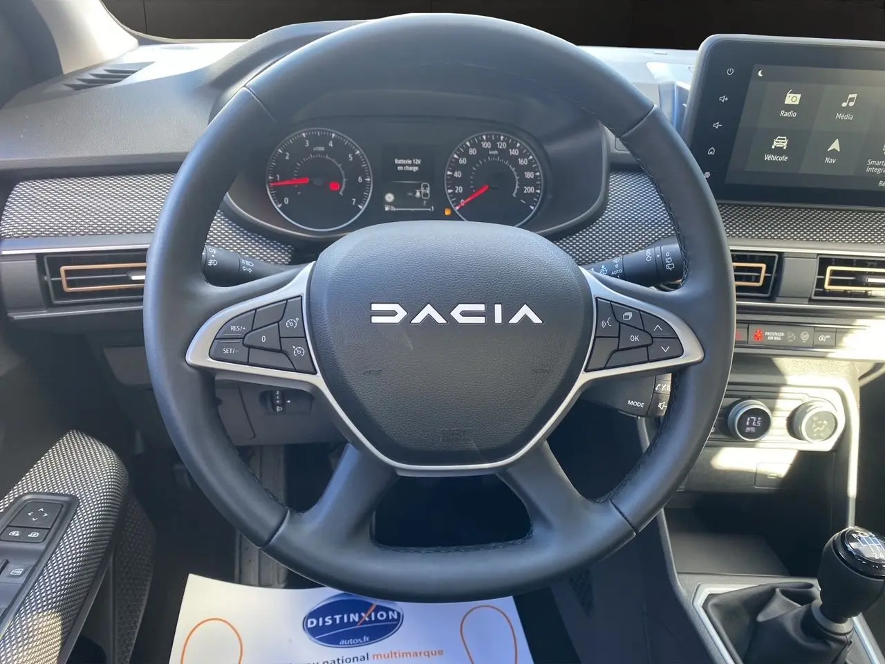 Vue centrée sur le volant noir DACIA avec tableau de bord et écran tactile Media Nav en arrière-plan.