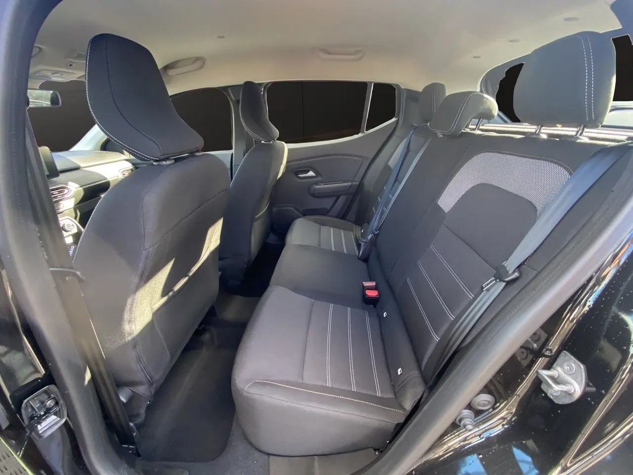 Vue intérieure côté droit arrière de la Dacia Sandero Stepway 2025 noire, montrant les sièges arrière en tissu noir.