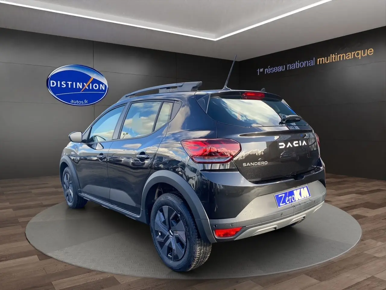 Vue 3/4 arrière droite d'une Dacia Sandero Stepway noire avec barres de toit et feux LED dans un showroom
