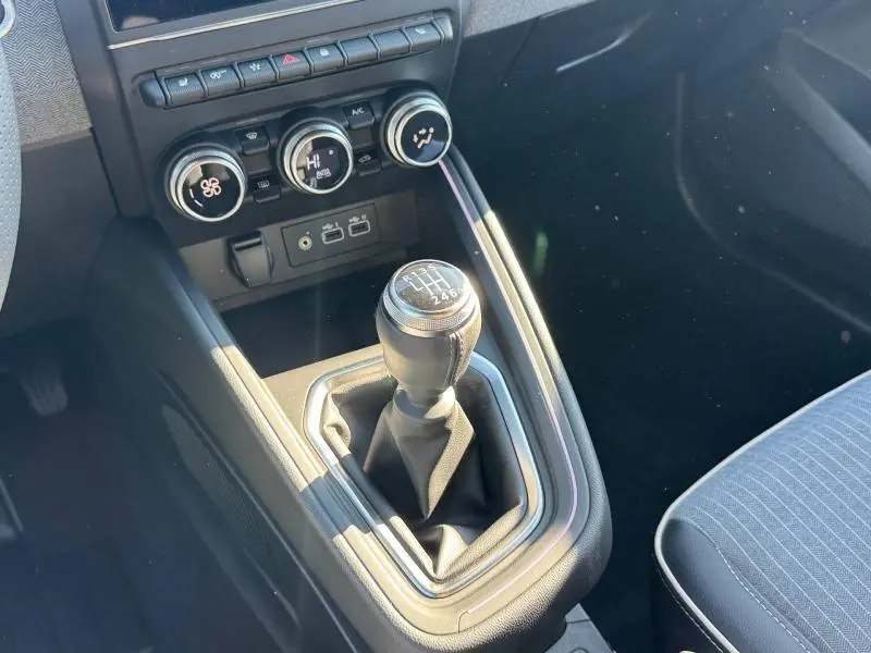 Gros plan sur le levier de vitesse manuel et la console centrale noire de la Renault Clio orange Valencia 2025.