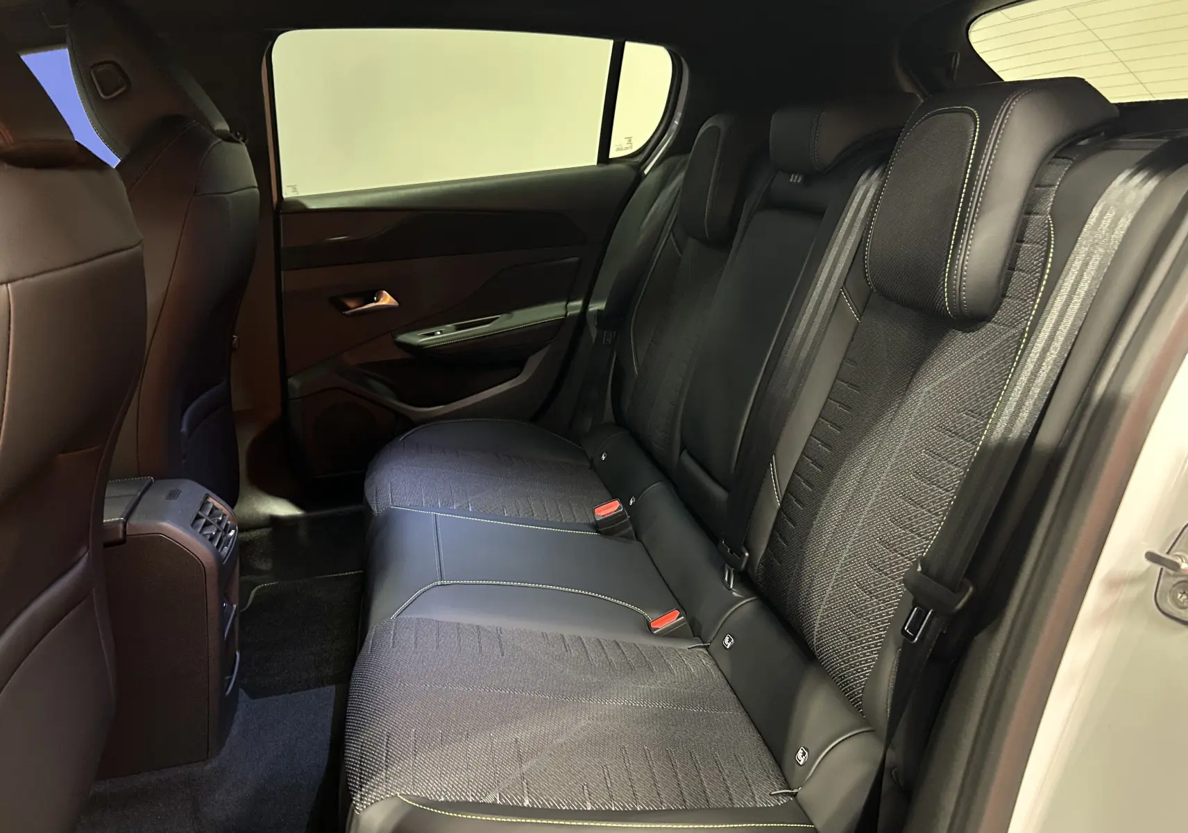 Vue intérieure côté droit des sièges arrière en cuir et tissu noir avec surpiqûres contrastantes du Peugeot 308 blanc Okenite.