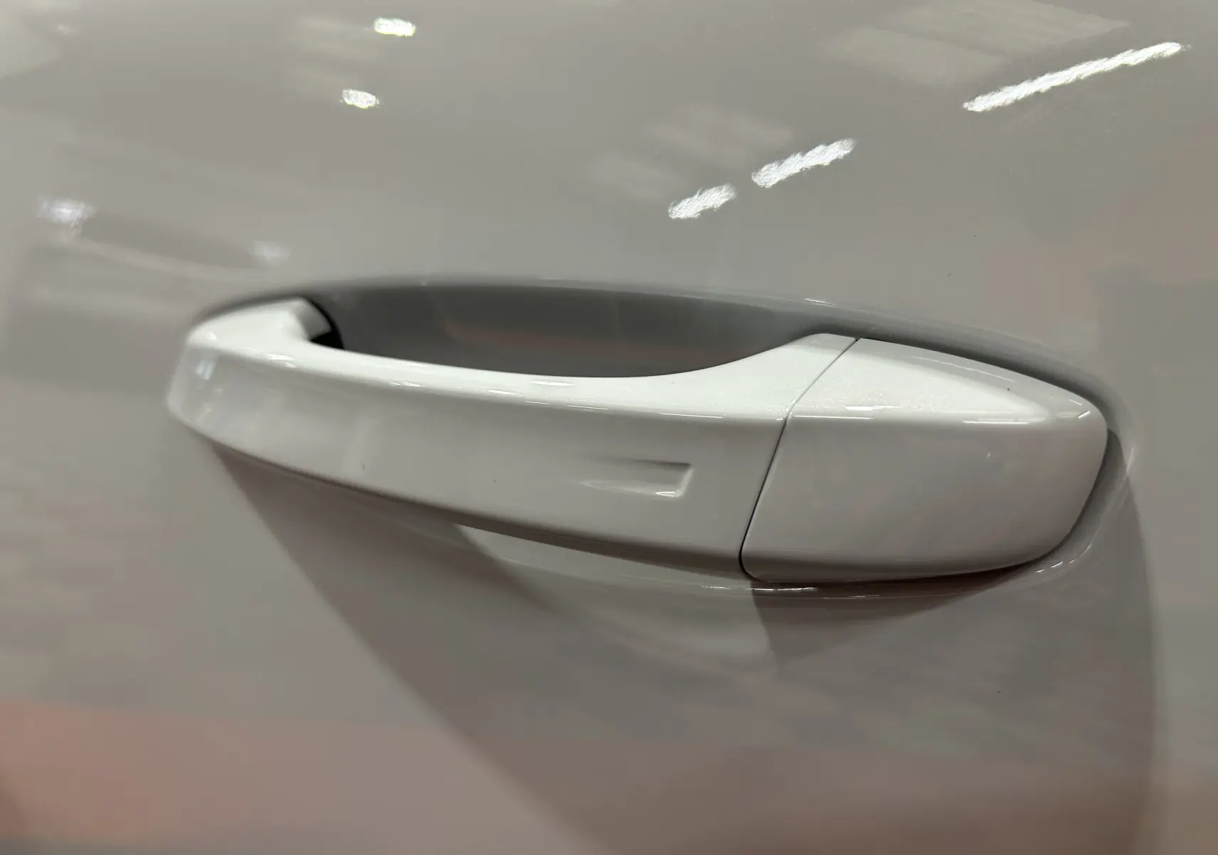 Poignée de porte blanche Okenite en gros plan sur une Peugeot 308 III Ph.2 Hybrid 145 GT, vue côté droit.