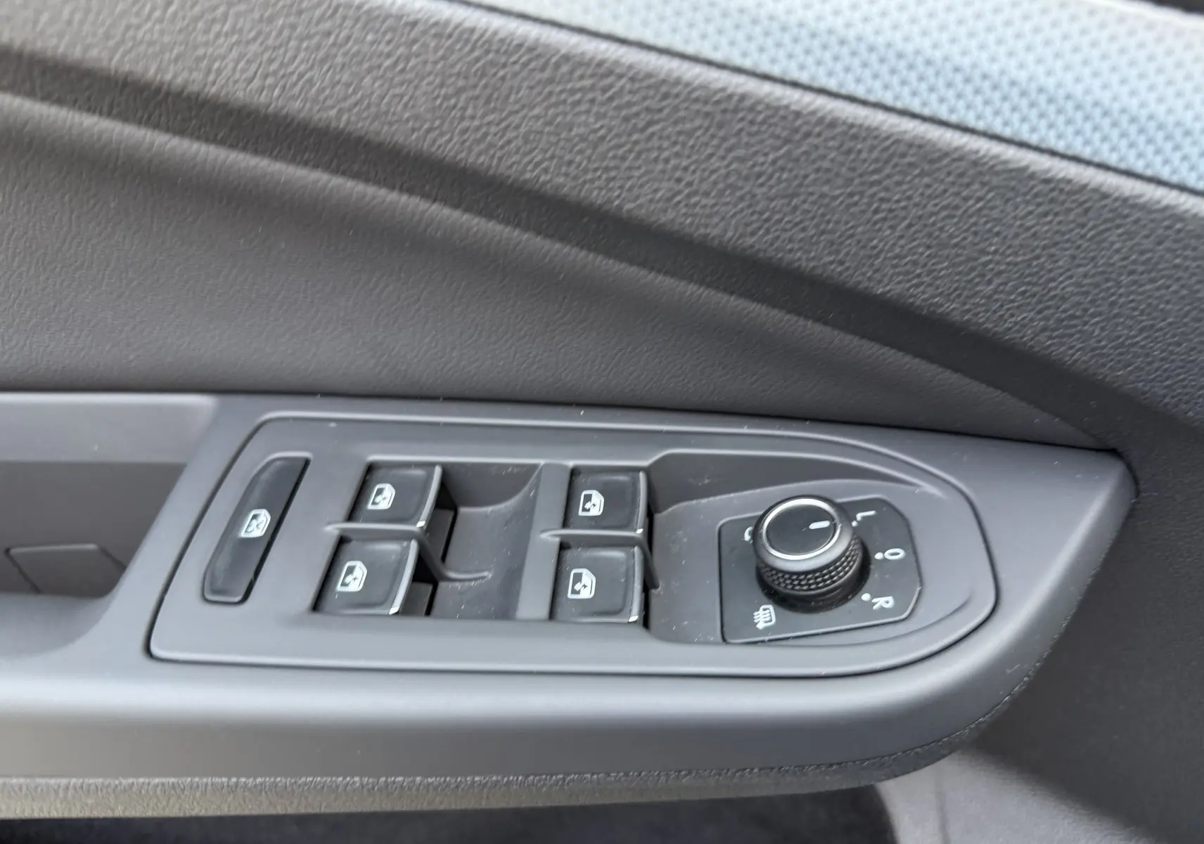 Détail des commandes de lève-vitres et réglage des rétroviseurs sur la porte côté gauche d’un Volkswagen Golf SW gris lunaire.