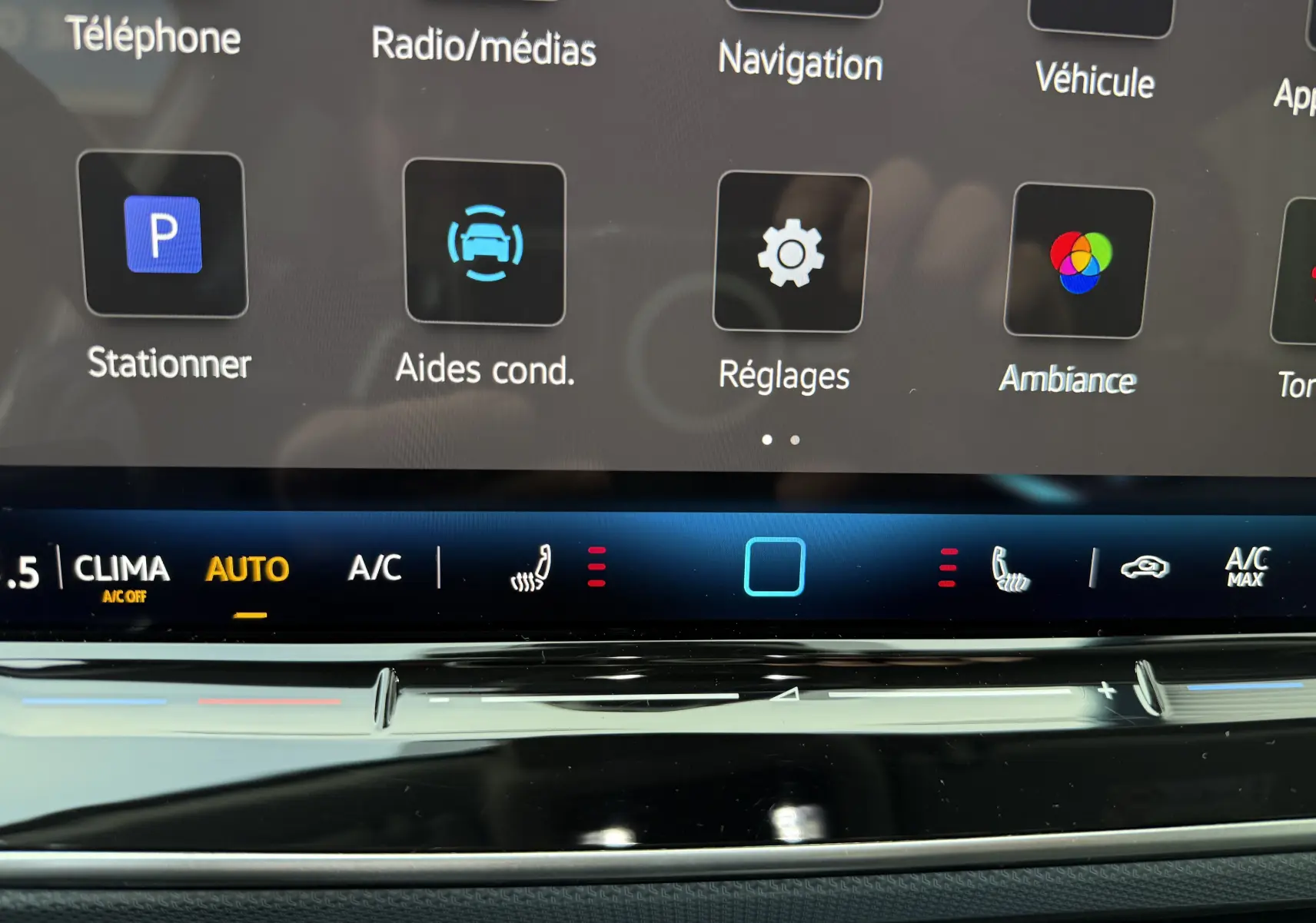 Vue rapprochée de l’écran tactile central de la Volkswagen Golf SW 2.0 TDI 150 gris lunaire, affichant les commandes de climatisation et aides à la conduite.