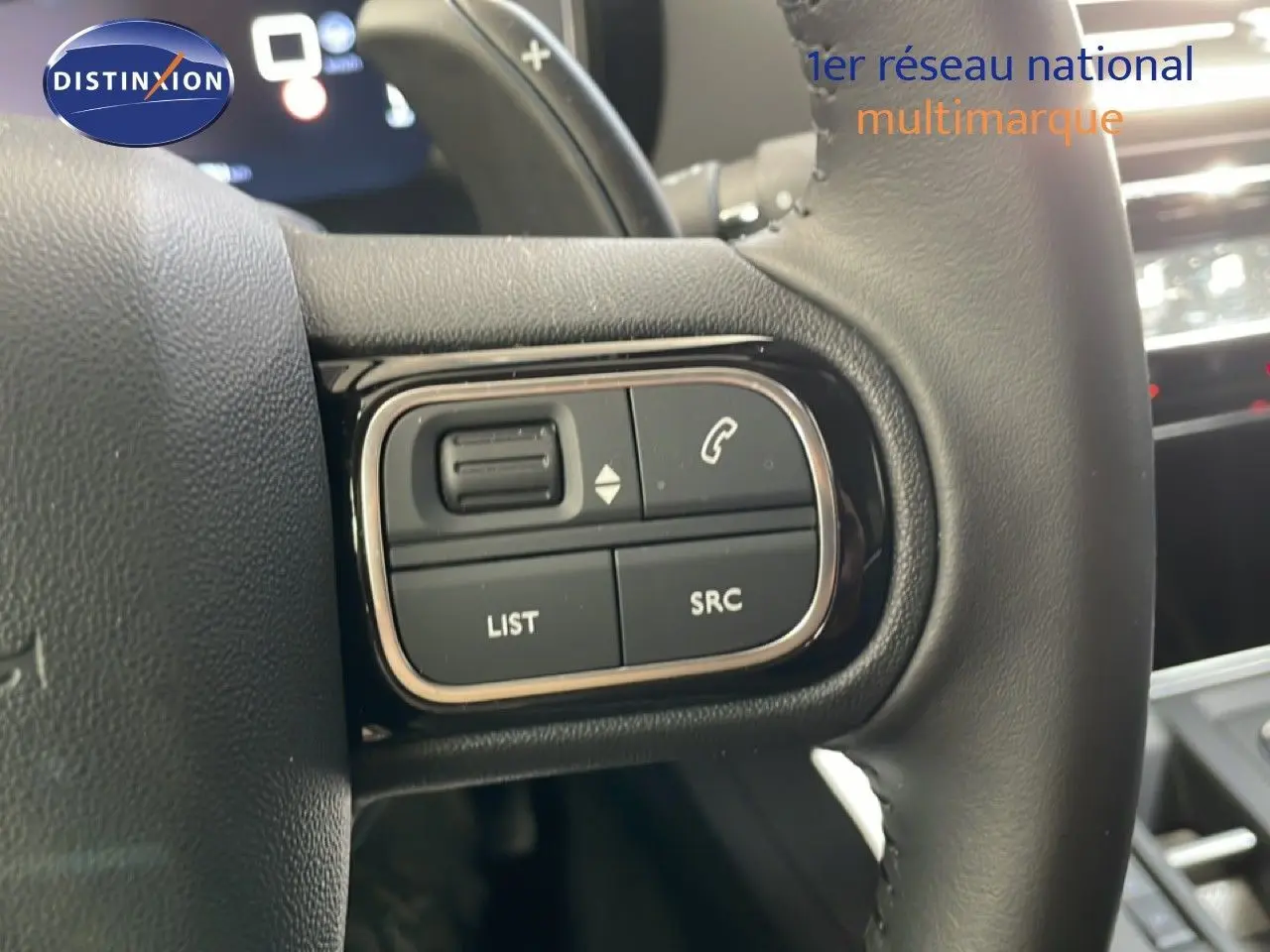Gros plan sur les commandes gauche du volant cuir noir du Citroën C5 Aircross gris platinium 2025, avec boutons multifonctions.