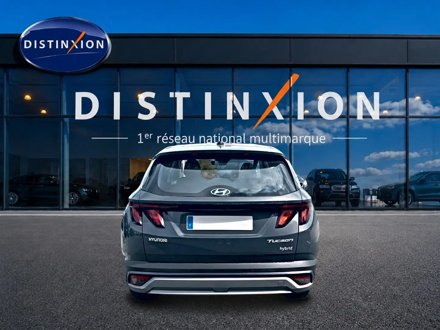 Vue arrière d'un Hyundai Tucson hybride gris ecotronique garé devant une vitrine avec logo Distinxion.
