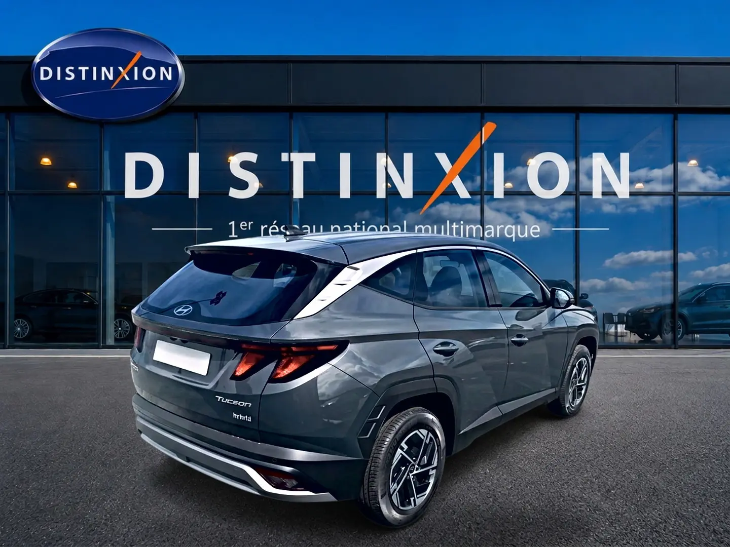 Vue 3/4 arrière droite du Hyundai Tucson gris écotronique avec jantes alliage et toit noir devant une vitrine Distinxion.