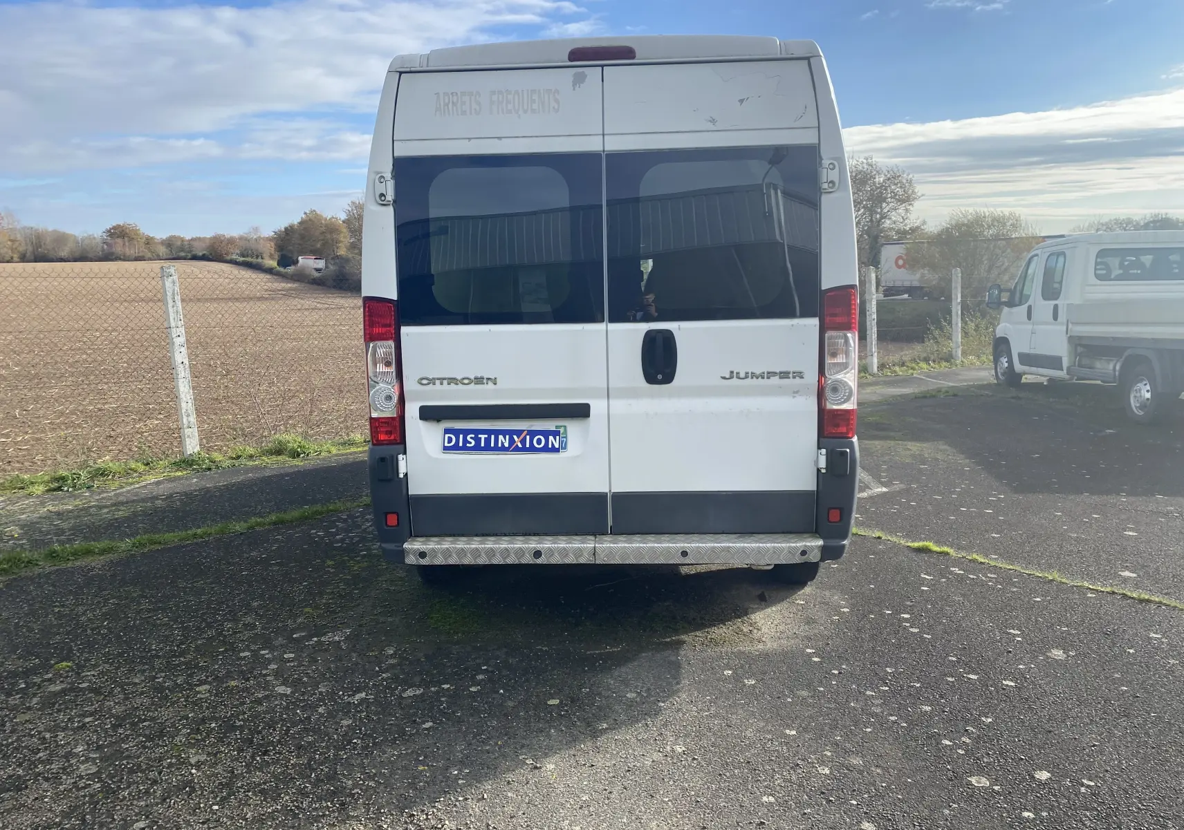 Vue arrière d'un utilitaire blanc Citroën Jumper L3H2 2011 avec marquage "ARRÊTS FRÉQUENTS" sur la porte supérieure.