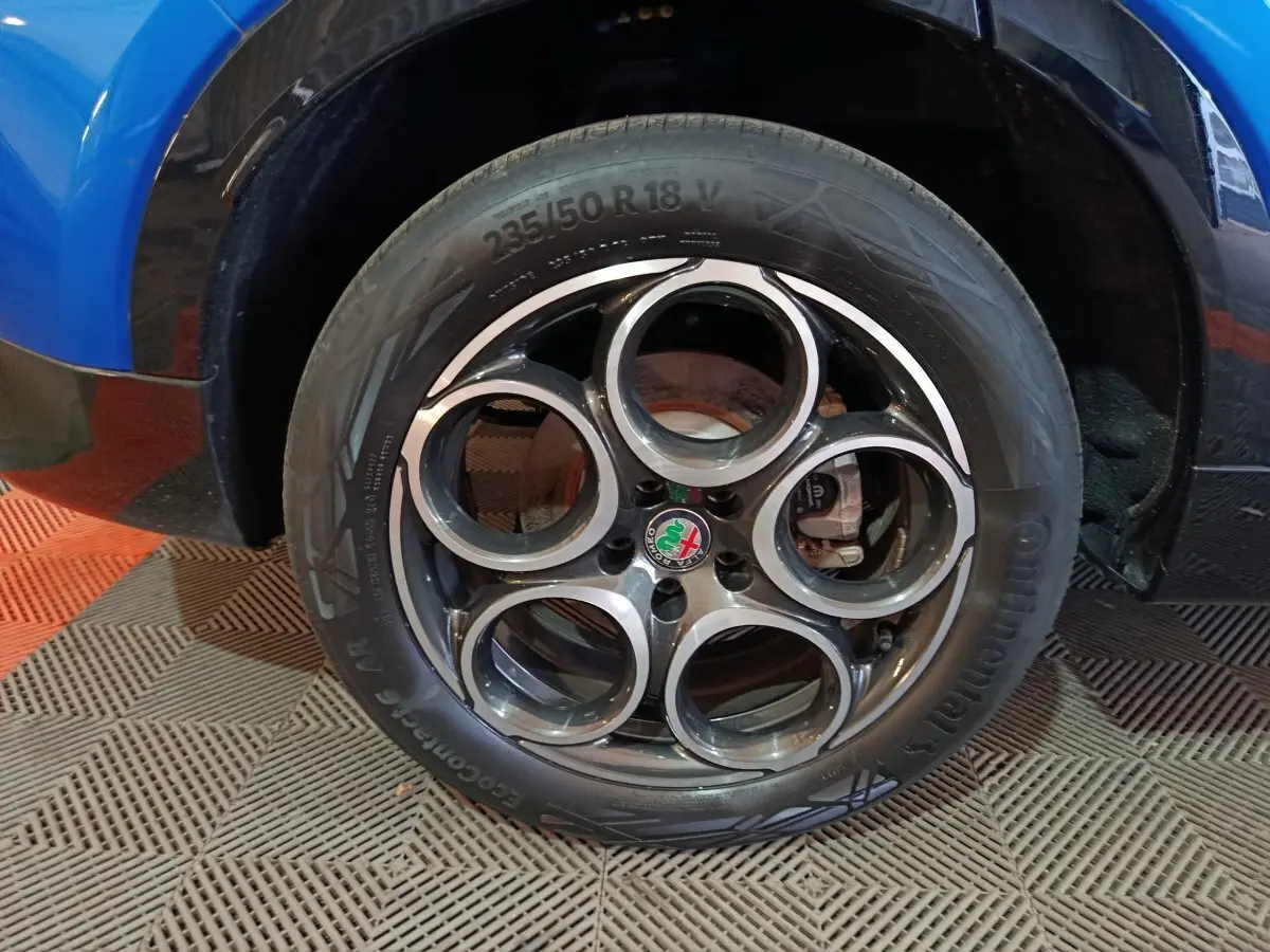 Gros plan sur la roue arrière droite d'une Alfa Romeo Tonale bleu 2023, avec passage de roue et partie basse de la carrosserie visibles.