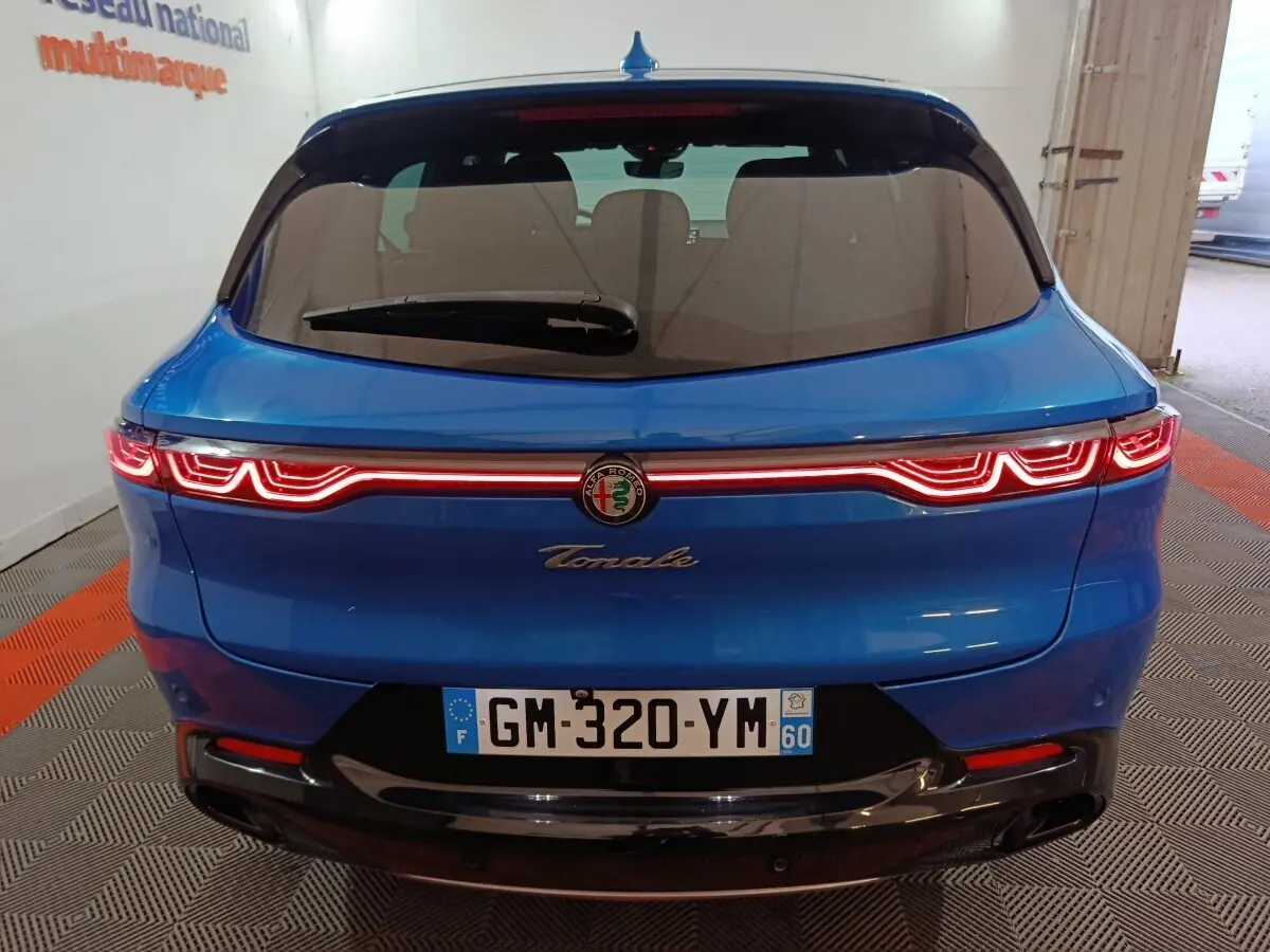 Vue arrière d'une Alfa Romeo Tonale bleu électrique avec feux arrière LED distinctifs allumés.