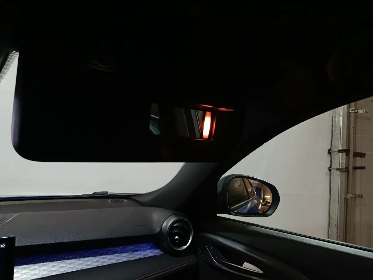 Intérieur côté passager de l'Alfa Romeo Tonale bleu, avec tableau de bord et rétroviseur latéral visible.