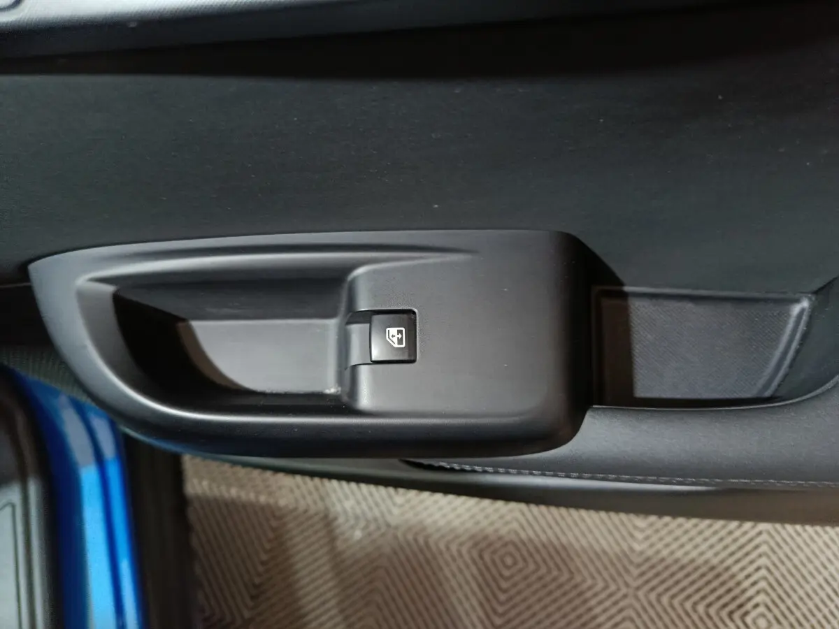 Gros plan sur la commande de lève-vitre côté gauche d'une Alfa Romeo Tonale bleu 2023, intérieur noir.