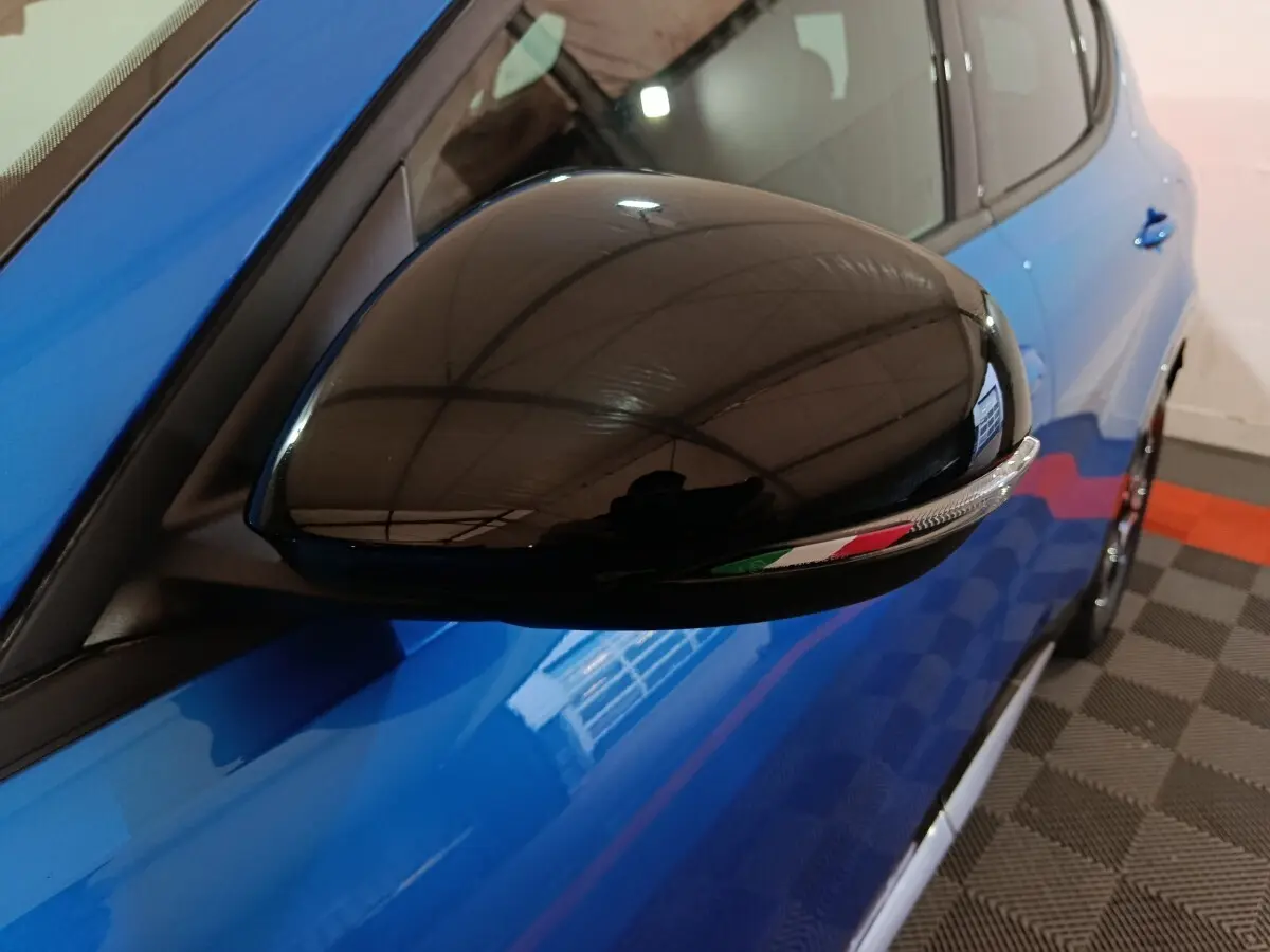 Gros plan sur le rétroviseur droit noir brillant avec drapeau italien, sur la portière bleue de l'Alfa Romeo Tonale 2023.
