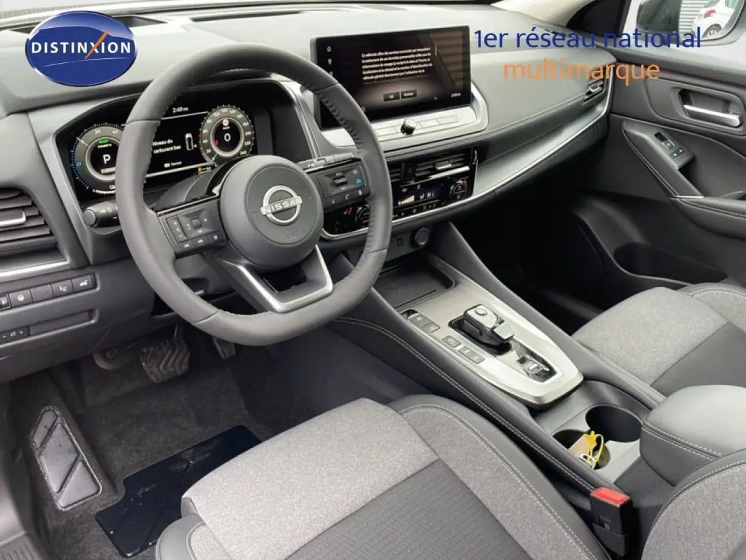 Intérieur du Nissan Qashqai 2025 gris, vue côté conducteur, volant cuir et écran tactile central lumineux.