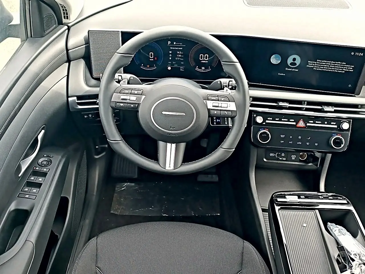 Vue intérieure frontale du tableau de bord gris du Hyundai Tucson 2026 avec volant cuir multifonction et écran digital large.