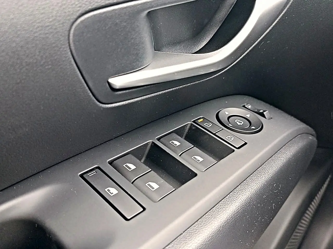 Gros plan sur les commandes de vitres électriques et rétroviseurs côté gauche du Hyundai Tucson gris Ecotronique 2026.