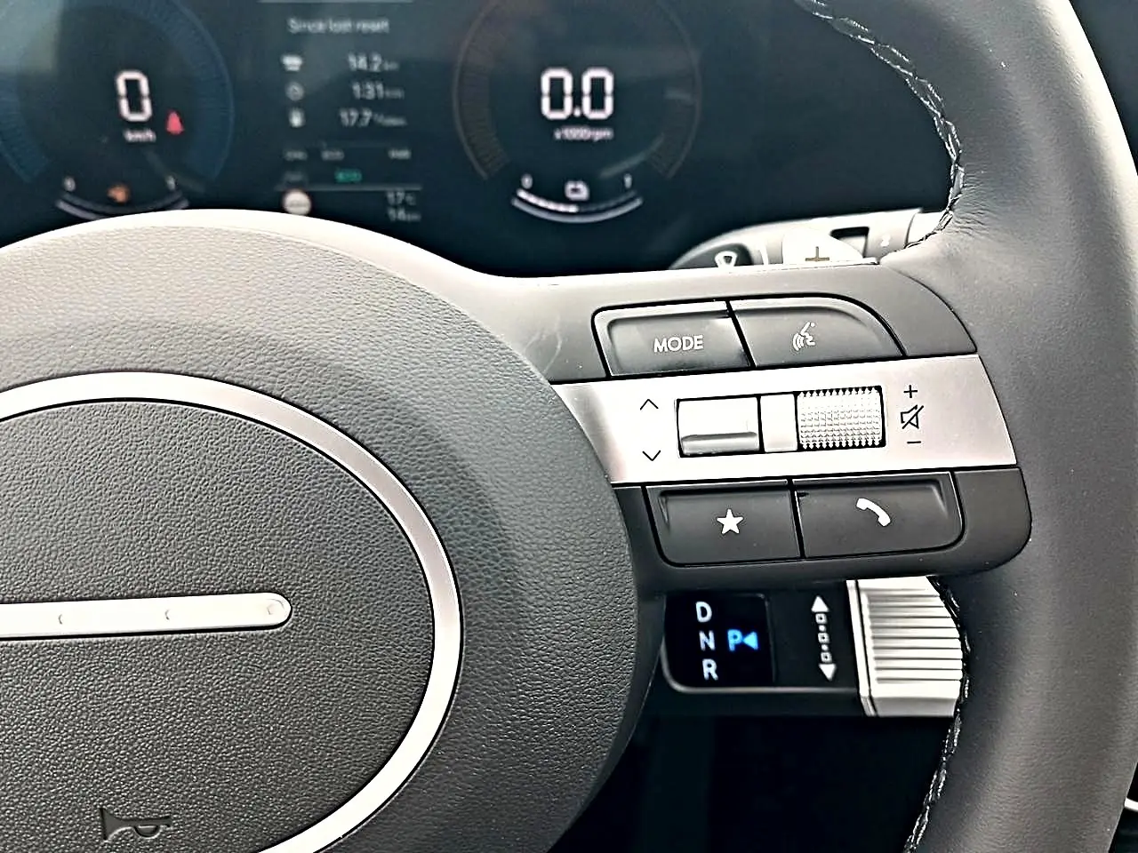 Gros plan sur le volant cuir multifonction du Hyundai Tucson gris, avec commandes audio et affichage numérique du tableau de bord.