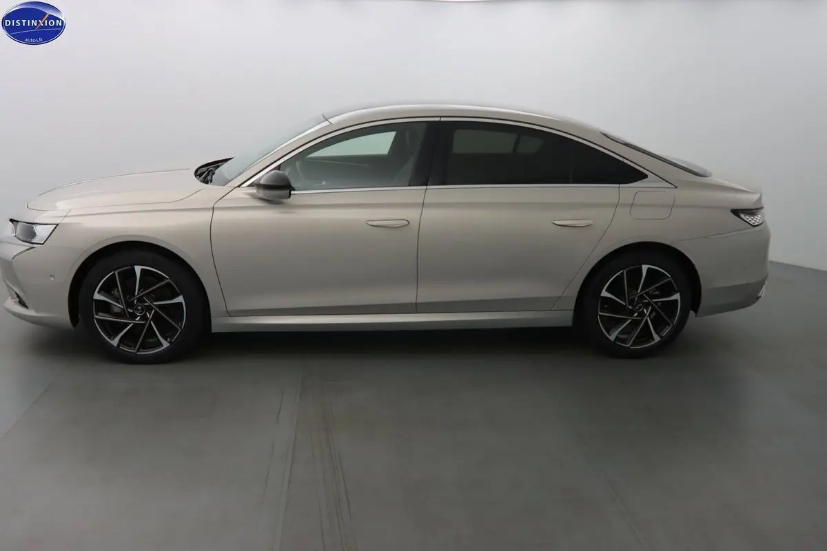 Profil côté gauche de la berline DS9 hybride rechargeable 2022 en couleur Crystal Pearl nacré métal avec jantes noires et argentées.