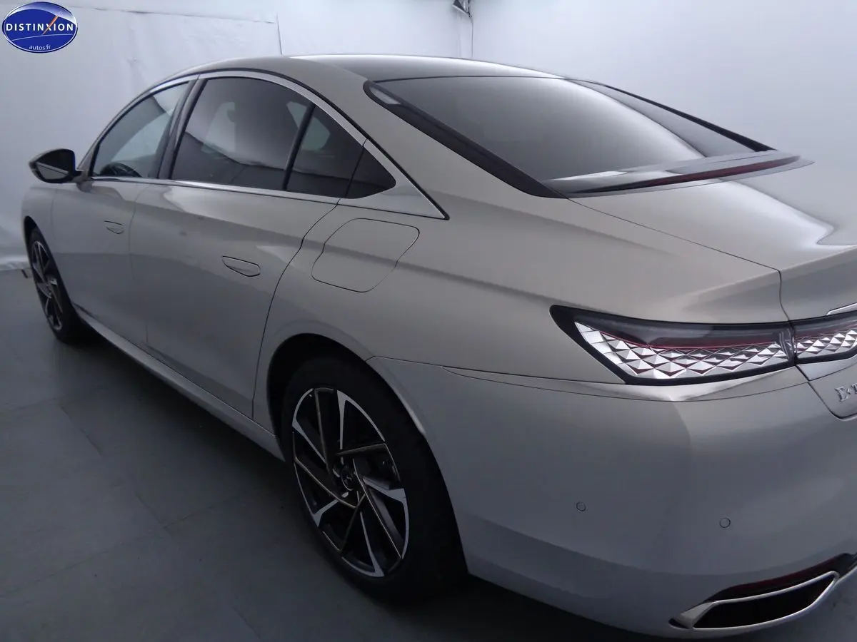 Vue 3/4 arrière droit d'une DS9 hybride rechargeable couleur Crystal Pearl nacré avec feux arrière à motif géométrique.