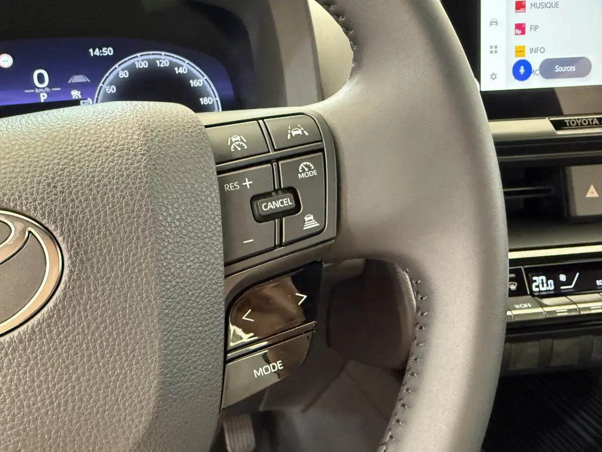 Gros plan sur le volant cuir multifonctions du Toyota C-HR 1.8 Hybride blanc, avec commandes de régulateur et écran tactile visible.