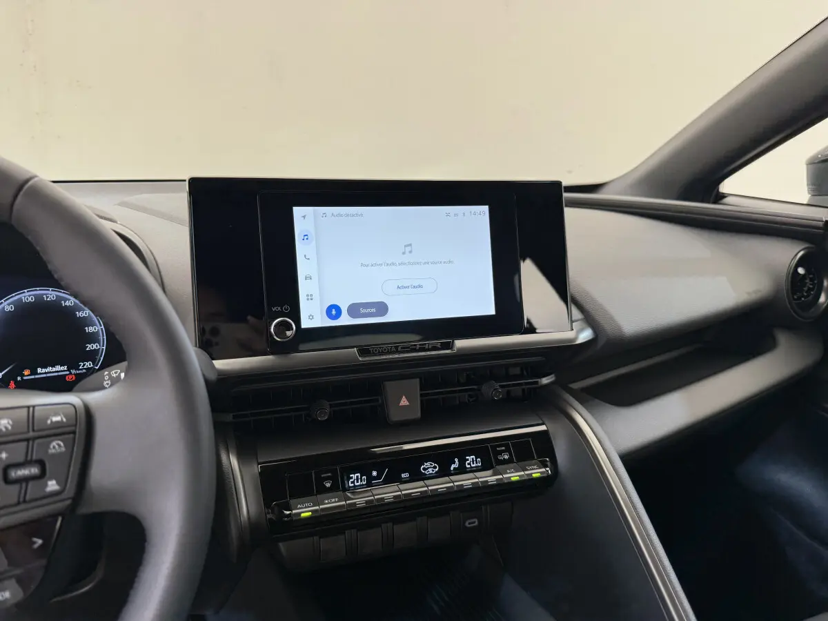 Vue intérieure du tableau de bord du Toyota C-HR 1.8 Hybride 2024 avec écran tactile central et commandes climatisation digitales.