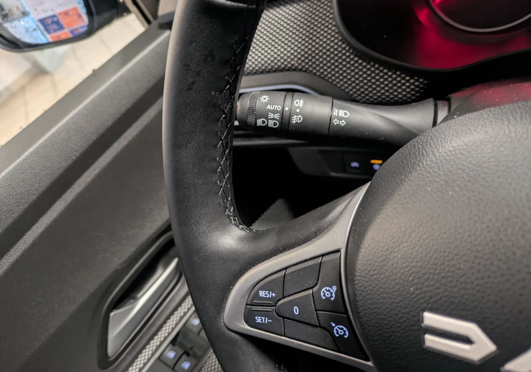 Gros plan sur le volant noir du Dacia Jogger 2025, avec commandes de régulateur de vitesse et manette d’éclairage visible.