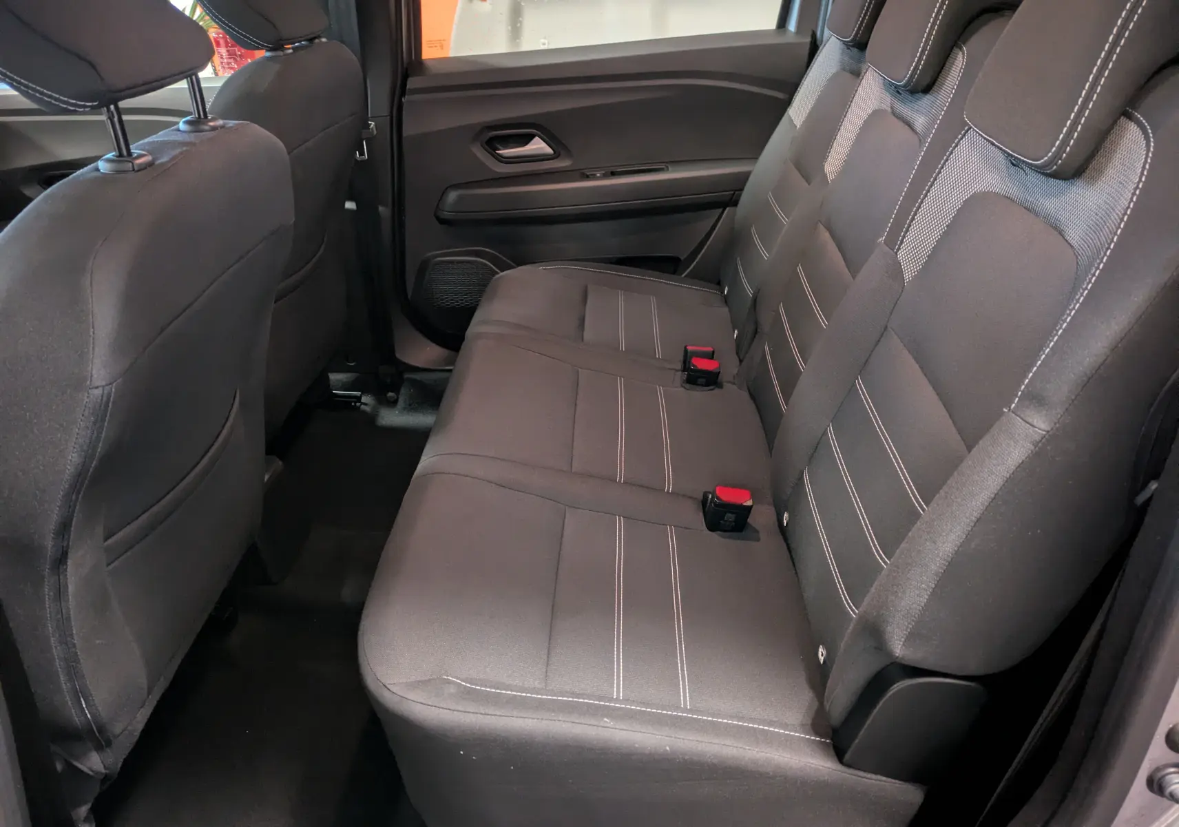 Vue intérieure côté droit des sièges arrière noirs avec surpiqûres blanches du Dacia Jogger 2025 gris schiste métal.